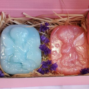 May include: Two small fairy-shaped soaps in a pink gift box. One soap is light blue and the other is pink with glitter.