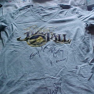 May include: A light blue t-shirt with a black and gold print of the band "Free Fall" with signatures from the band members: "Gary Moore", "Mike Barlay", and "F. Urner".