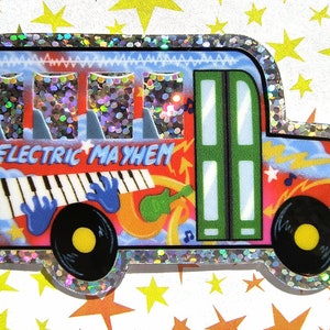 Könnte beinhalten: Ein roter, blauer und grüner Schulbus mit dem Schriftzug "Electric Mayhem" an der Seite. Der Bus hat einen glitzernden silbernen Rand und ist mit Noten, Blitzen und einer Tastatur verziert.