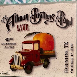 May include: A DVD case featuring a red truck with a peach on top. The text on the case reads "The Allman Brothers Band Live 40th Anniversary 1969-2009 Houston, TX October 17, 2009".