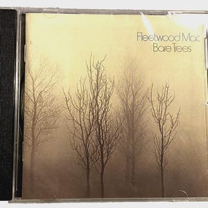 May include: A CD case featuring the album "Bare Trees" by Fleetwood Mac. The cover art depicts bare trees in a misty, sepia-toned landscape. The album title and artist name are printed in a simple, sans-serif font.