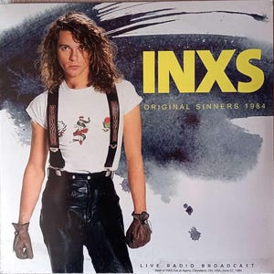 May include: A vinyl record cover featuring a person with long wavy hair wearing a white t-shirt with a graphic, black suspenders, black pants, and brown gloves. The text reads INXS ORIGINAL SINNERS 1984 LIVE RADIO BROADCAST and details about the concert.