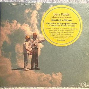May include: A sealed CD of Ben Folds' "What Matters Most" limited edition album. The cover art features two figures standing on clouds. A yellow sticker includes text about the album, including "Includes Autographed Insert" and "3 Exclusive Bonus Tracks."