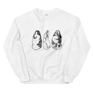 May include: White sweatshirt with a black and white illustration of three stone tools.