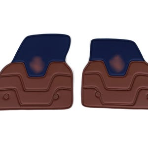 May include: Two car floor mats. Each mat has a brown base with a textured design and a dark blue upper section. The mats are designed to fit the driver and passenger sides of a vehicle.