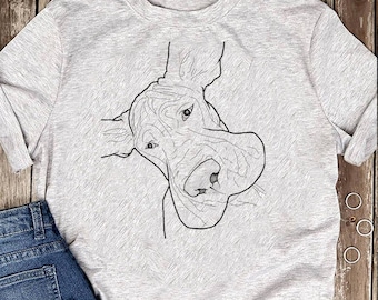 Può includere: Una maglietta grigia con un disegno a linea nera della testa di un cane. Il cane guarda lo spettatore con la lingua di fuori.