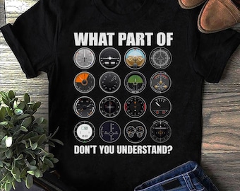 May include: Black t-shirt with the text "WHAT PART OF DON'T YOU UNDERSTAND?" above a grid of aviation instrument gauges. The shirt is made of a dark fabric and features a crew neck. The design is printed in white.