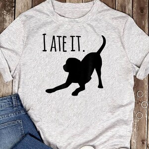 May include: Gray t-shirt with the text "I ATE IT." and a black silhouette of a dog.