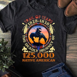 May include: Dark grey t-shirt with a circular graphic depicting a Native American on horseback. The graphic includes the text "Trail of Tears 1828-1838", "The Deadly Journey", and "125,000 Native American".