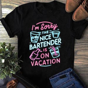 Könnte beinhalten: Schwarzes T-Shirt mit einem Neon-Grafik-Design, das besagt: "I'm Sorry The Nice Bartender Is On Vacation." Das Design beinhaltet Cocktailgläser und eine Flaschenillustration. Das Shirt wird mit blauen Jeans und braunen Schuhen gezeigt.