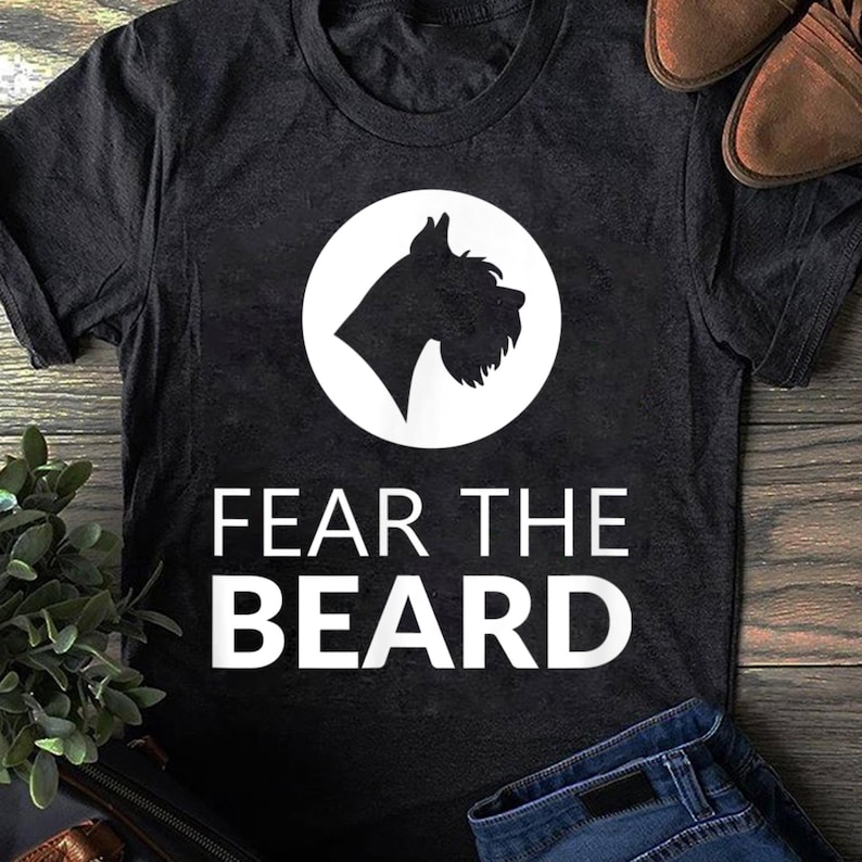 May include: Black t-shirt with a white circle containing a silhouette of a Schnauzer dog. The text "FEAR THE BEARD" is printed in white below the circle.