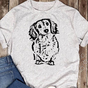 May include: A gray t-shirt with a black and white illustration of a dachshund dog.