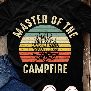 May include: A black t-shirt with a vintage-style graphic of a campfire with the text "Master of the Campfire" in white.