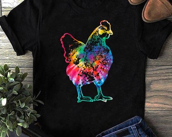 Pode incluir: Uma camiseta preta com um design de frango arco-íris tie-dye.