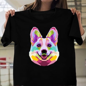 May include: A black t-shirt with a colorful, geometric design of a corgi dog. The dog's face is highlighted with pink, yellow, green, and blue.