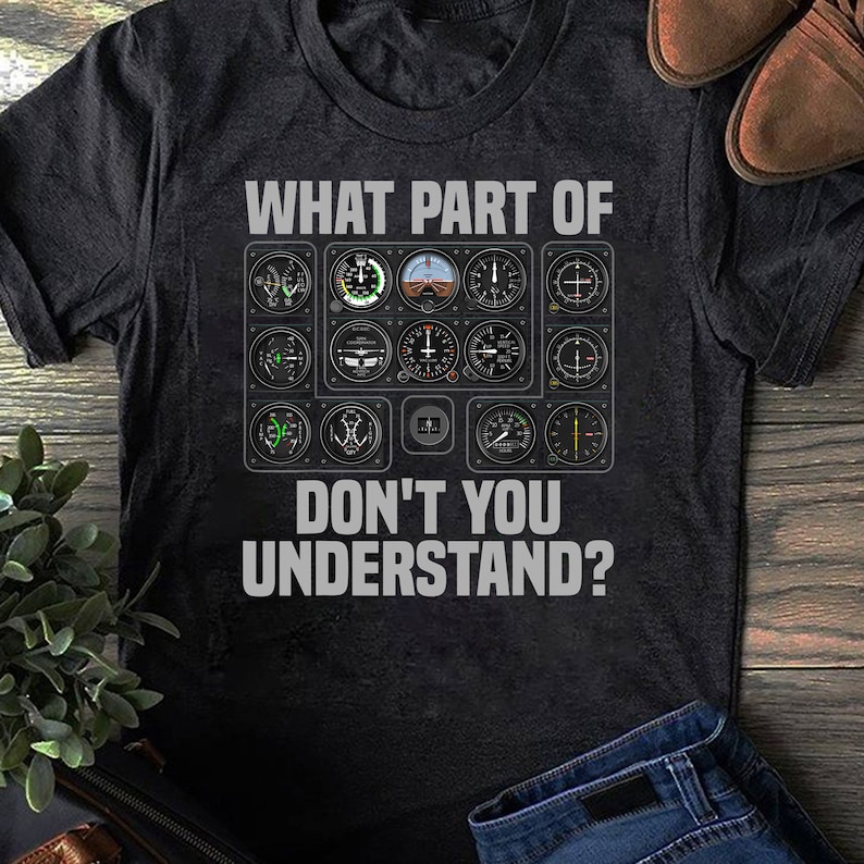 May include: A black t-shirt featuring a graphic of an aircraft cockpit instrument panel and the text "WHAT PART OF DON'T YOU UNDERSTAND?"
