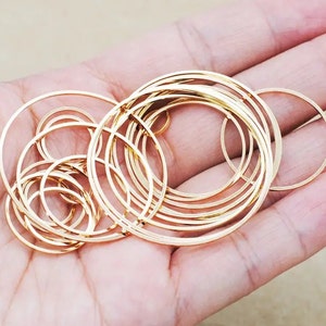 May include: A set of gold-coloured metal hoops of varying sizes, arranged in a circular pattern. The hoops are stacked on top of each other, creating a layered effect.