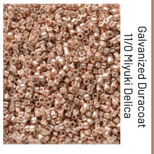 Pode incluir: Uma coleção de pequenas contas cilíndricas de ouro rosa metálico rotuladas como Galvanized Duracoat 11/0 Miyuki Delica. Estas contas de vidro uniformes e cortadas com precisão apresentam um acabamento brilhante e reflexivo com uma forma tubular constante.