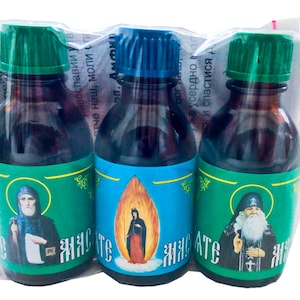 May include: Three small glass bottles with green, blue, and green caps. Each bottle contains a dark liquid and has a label with a religious image and the word "Живите" in Cyrillic script.