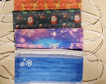 May include: A stack of six disposable face masks featuring various holiday patterns. Designs include a reindeer, the word Joy with a candy cane, orange reindeer, Santa Claus with reindeer, a purple snowflake pattern, and a blue snowflake design.