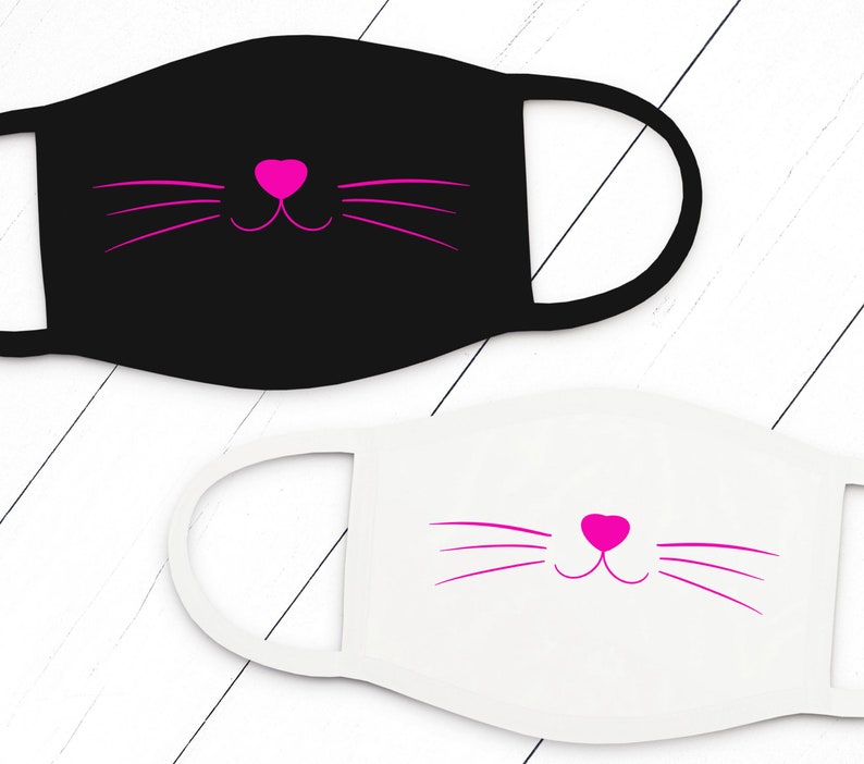 May include: Two cloth face masks with a pink cat face design. One mask is black and the other is white.