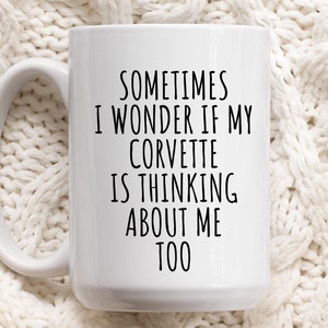 Könnte beinhalten: Weiße Keramik-Kaffeetasse mit schwarzem Text, der lautet: "Manchmal frage ich mich, ob mein Corvette an mich denkt."