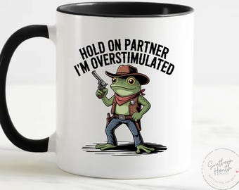 Funny Cowboy Frog Coffee Mug – Hold On Partner I’m Overstimulated – Meme Gift – White Ceramic Cup