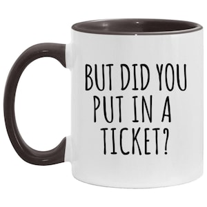 Op de afbeelding: Witte koffiemok met een zwarte handgreep en zwarte rand. De mok heeft de tekst "But did you put in a ticket?" in zwart gedrukt.