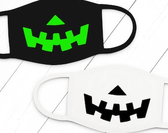May include: Two face masks with a jack-o'-lantern design. One mask is black with a green jack-o'-lantern face, and the other mask is white with a black jack-o'-lantern face.