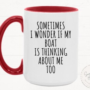May include: White ceramic mug with a red handle and interior. The mug features the text "SOMETIMES I WONDER IF MY BOAT IS THINKING ABOUT ME TOO" in black. A small circular logo is visible on the right side.