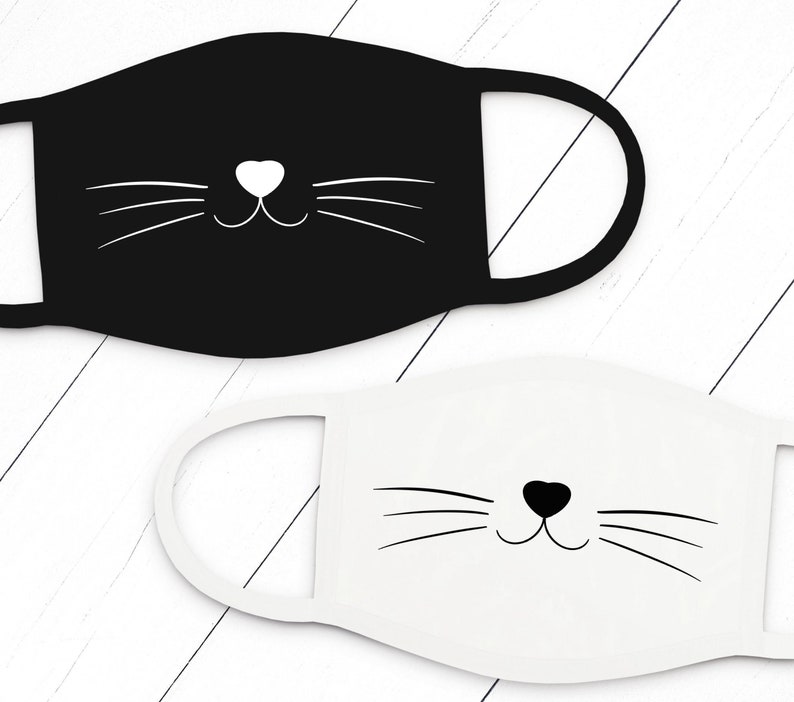 May include: Two face masks, one black and one white, with a simple cat face design. The cat face features a white heart nose and black whiskers.