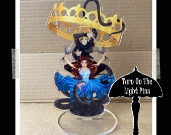 May include: An acrylic stand featuring a black snake, two figures wielding swords, and a gold crown. The stand includes the text "Turn On The Light Pins" on a black lampshade.