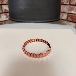 May include: A copper bracelet made of small, round, connected pieces.