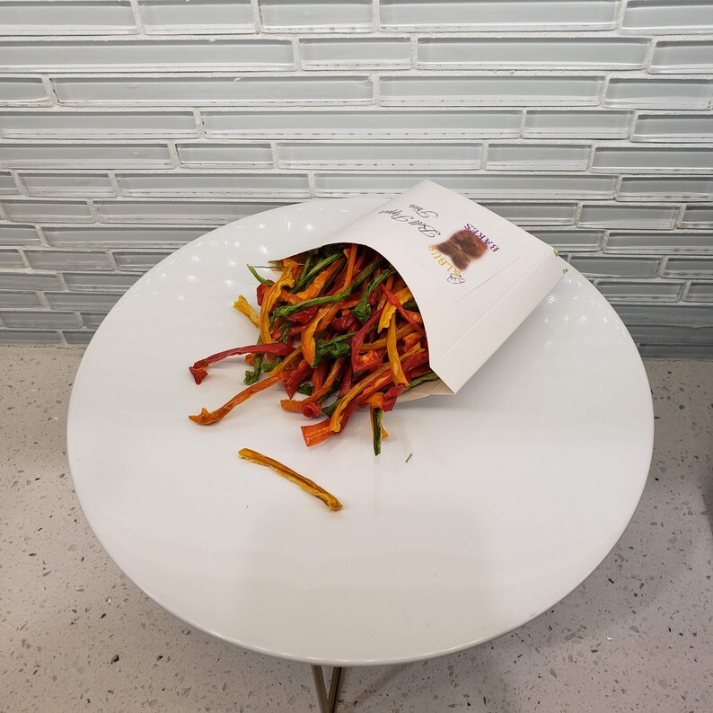 May include: A white paper bag with the text "Raw Bites" printed on it, filled with a colorful mix of dried vegetable strips.