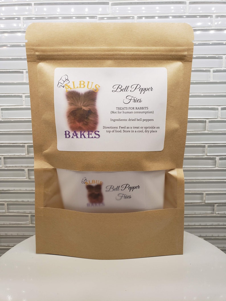 May include: A brown paper bag with a white label that says "Albus Bakes Bell Pepper Fries Treats for Rabbits (Not for human consumption) Ingredients: dried bell peppers Directions: Feed as a treat or sprinkle on top of food. Store in a cool, dry place"