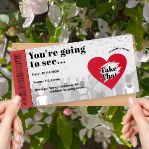 K&ouml;nnte beinhalten: Ein Rubbellos mit dem Text "You're going to see..." und "Take That" in einem roten Herzen. Das Datum ist der 16.04.2026, und der Veranstaltungsort ist 02 Arena. Die Nachricht lautet: Frohe Weihnachten, lasst uns feiern...