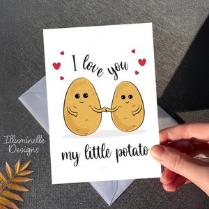 May include: A white card with a cute illustration of two potatoes holding hands. The card says "I love you my little potato" with red hearts around the text.