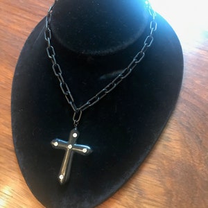 Black Bakelite cross with rhinestones accents on a celluloid chain.