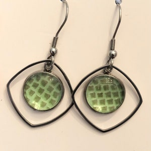 May include: A pair of silver earrings with a green geometric pattern inside a diamond-shaped frame.