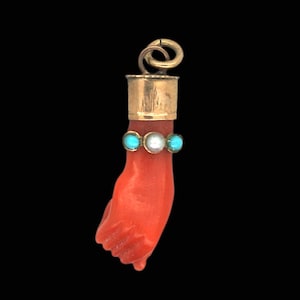 Puede incluir: Un colgante de mano de coral rojo con parte superior dorada y detalles en turquesa y perla.