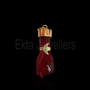 Könnte beinhalten: Einzigartiger Anhänger in Handform, tiefrot, mit goldfarbener Kappe und einem goldenen Ring mit türkisfarbenen Steinen. Der Anhänger hat eine Schlaufe für eine Kette und ist vor schwarzem Hintergrund platziert.