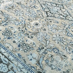 May include: A vintage rug with a blue and white floral pattern. The rug has a faded look and a dark blue border.