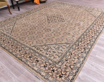 May include: Large rectangular beige rug with an intricate geometric pattern. The rug features a central medallion and a detailed border with floral and geometric motifs. The color palette includes beige, black, and touches of blue.