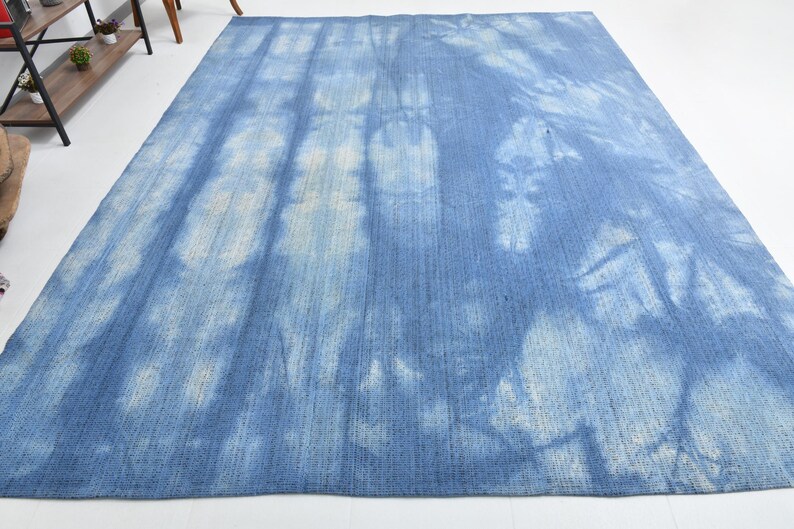 Pu&ograve; includere: Un tappeto blu e bianco tie-dye con una texture sottile. Il tappeto ha un aspetto sbiadito e vintage.