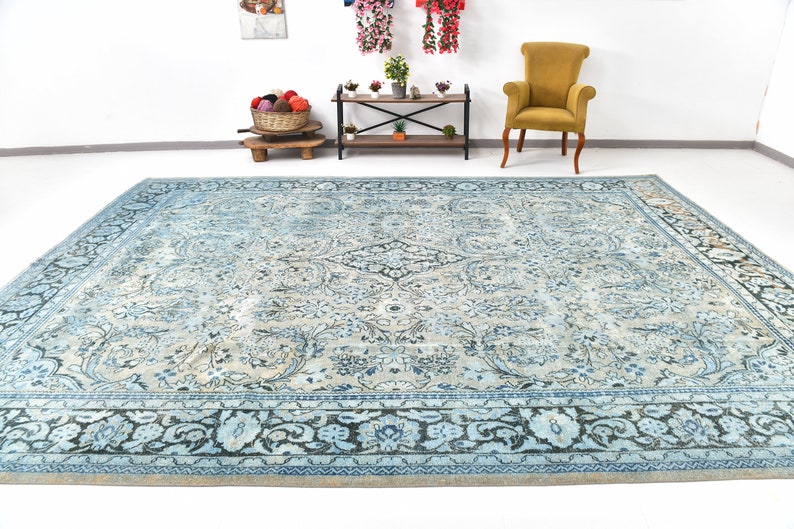 May include: A vintage blue and cream rug with a floral pattern and a dark blue border. The rug is laid out on a white floor.
