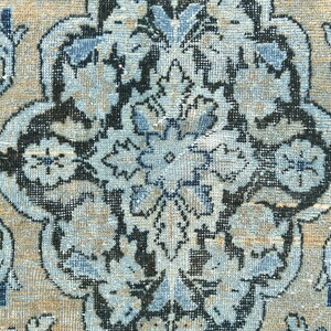 May include: A close-up of a blue and beige patterned rug with intricate floral designs. The rug has a traditional Persian style and features a central medallion.