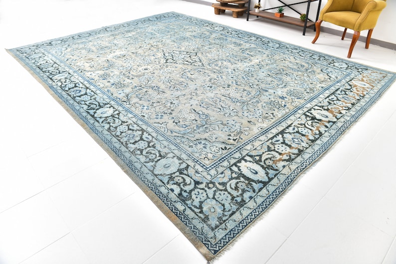 May include: A vintage blue and white rug with a floral pattern and a black border. The rug has a distressed look and is made of wool.