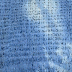 Pu&ograve; includere: Un tessuto blu con un sottile motivo blu chiaro. Il tessuto ha una trama tessuta e una superficie leggermente ruvida.