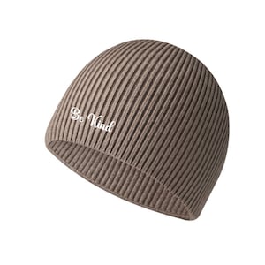 May include: A ribbed, taupe beanie hat with the embroidered text "Be Kind" in white. The hat is made of a soft, knitted material and is designed to fit snugly on the head. The hat is a neutral color, making it versatile for various outfits.
