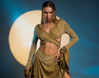 May include: A woman wearing a long, flowing, olive green dress with a wrap top. The dress has a loose, flowing fit and is made of a soft, drapey fabric. The woman is standing in front of a large, bright, yellow moon.